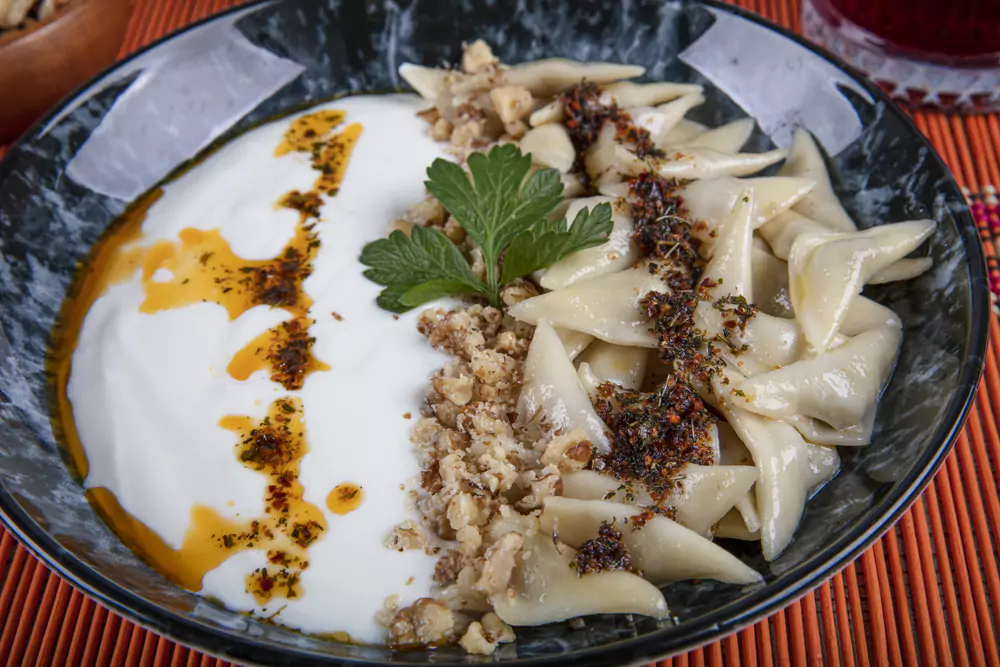 Top 8 Traditional Turkish Food in Istanbul (Beyond Kebabs and Baklava) 5 Turkish cuisine, Samsun style ravioli. Turkish ravioli manti preparation with meat, yoghurt, butter and red pepper. Manti concept, Anatolian foods on the table.