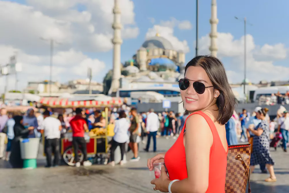 where to buy souvenirs in Istanbul: Beautiful Chinese woman poses at at Eminonu district with view of Suleymaniye mosque in Istanbul